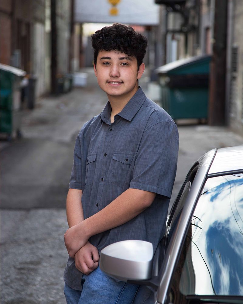 Senior leaning on a car in an alley